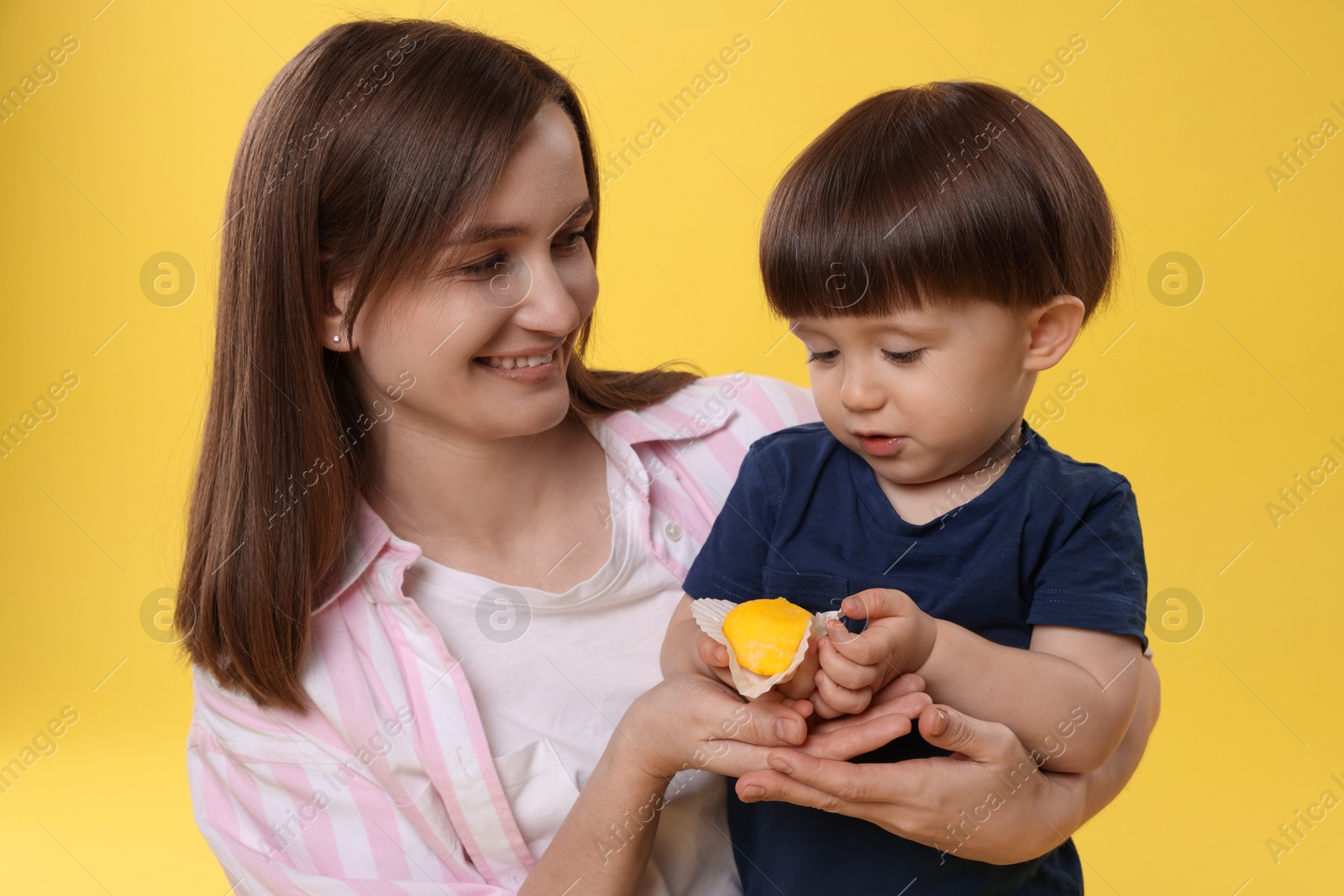 Photo of Mother and baby eating tasty mochi on yellow background