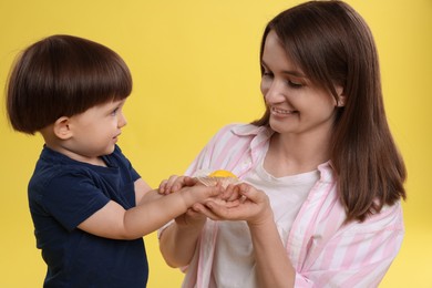 Photo of Mother and baby eating tasty mochi on yellow background