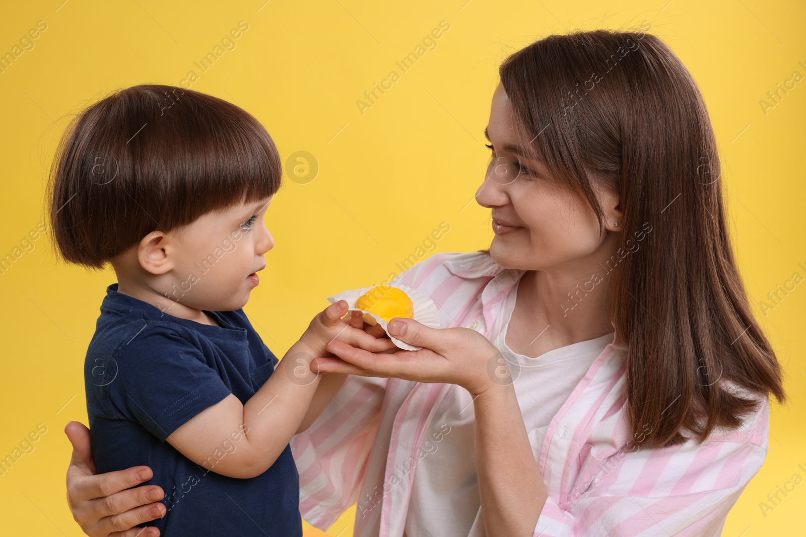 Photo of Mother and baby eating tasty mochi on yellow background