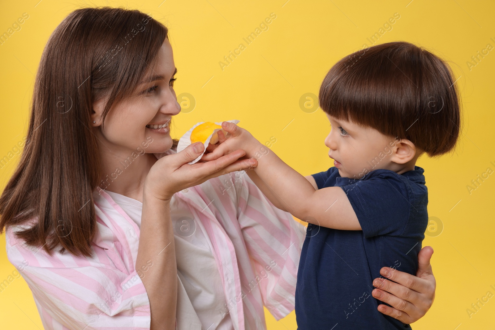 Photo of Mother and baby eating tasty mochi on yellow background