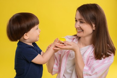 Photo of Mother and baby eating tasty mochi on yellow background