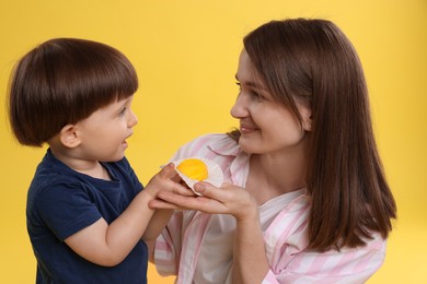 Photo of Mother and baby eating tasty mochi on yellow background