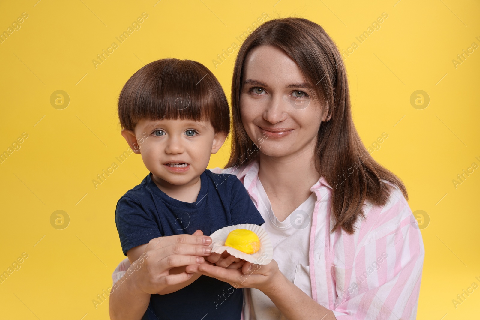 Photo of Mother and baby eating tasty mochi on yellow background