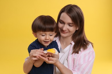 Photo of Mother and baby eating tasty mochi on yellow background