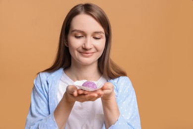 Photo of Woman with tasty mochi on light brown background