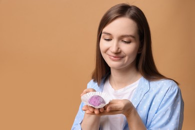 Photo of Woman with tasty mochi on light brown background. Space for text