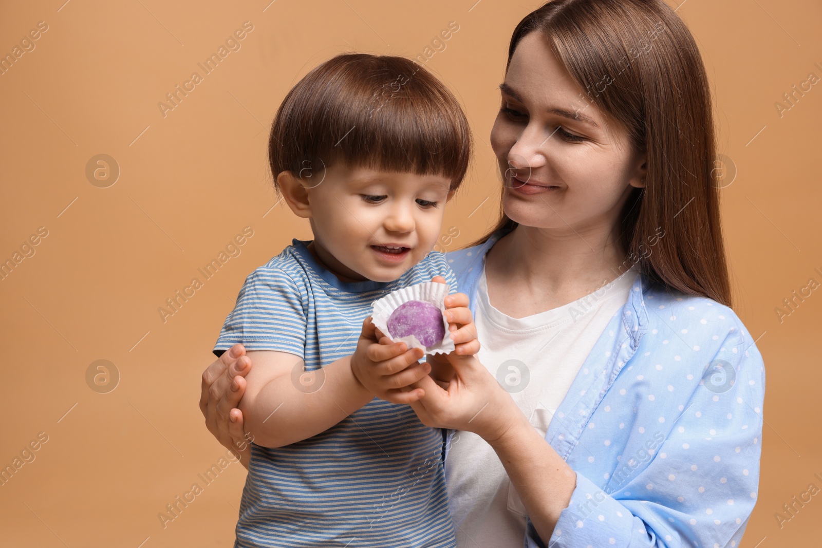 Photo of Mother and baby eating tasty mochi on brown background