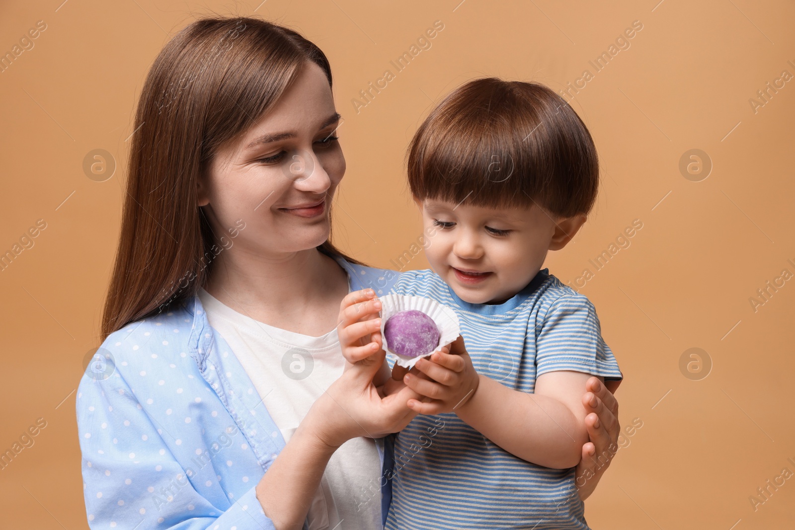 Photo of Mother and baby eating tasty mochi on brown background