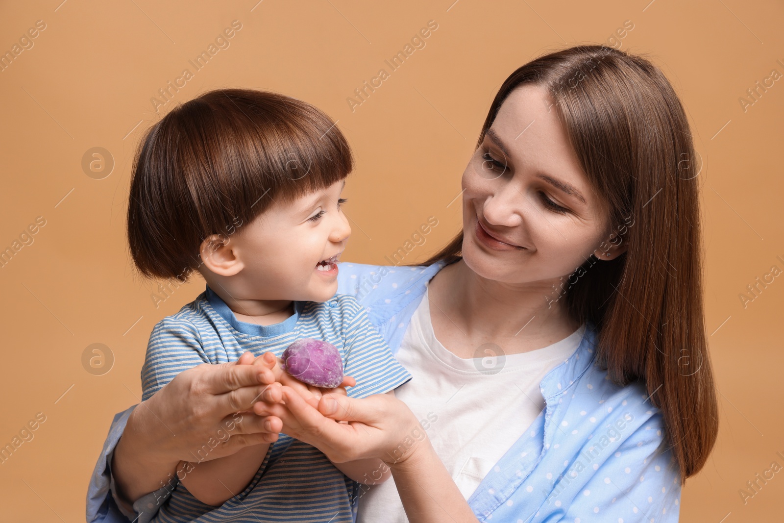 Photo of Mother and baby eating tasty mochi on brown background