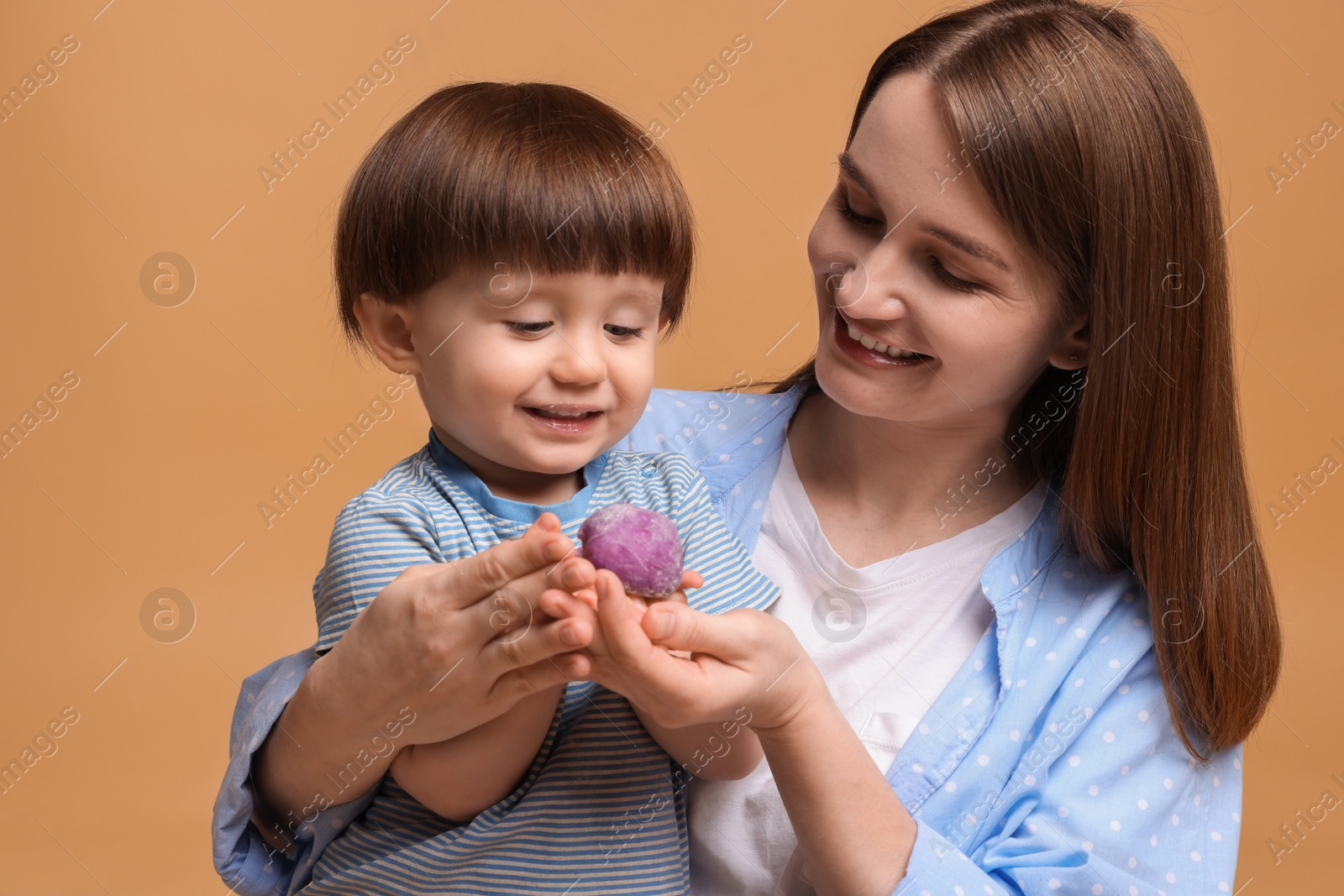 Photo of Mother and baby eating tasty mochi on brown background