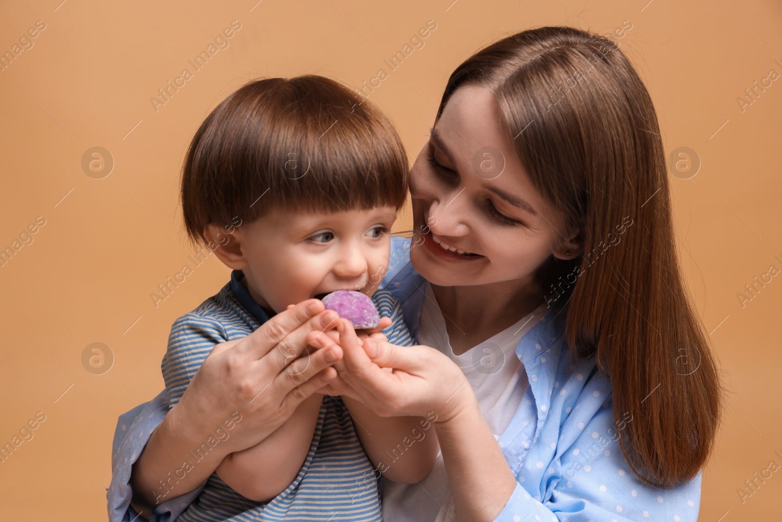 Photo of Mother and baby eating tasty mochi on brown background