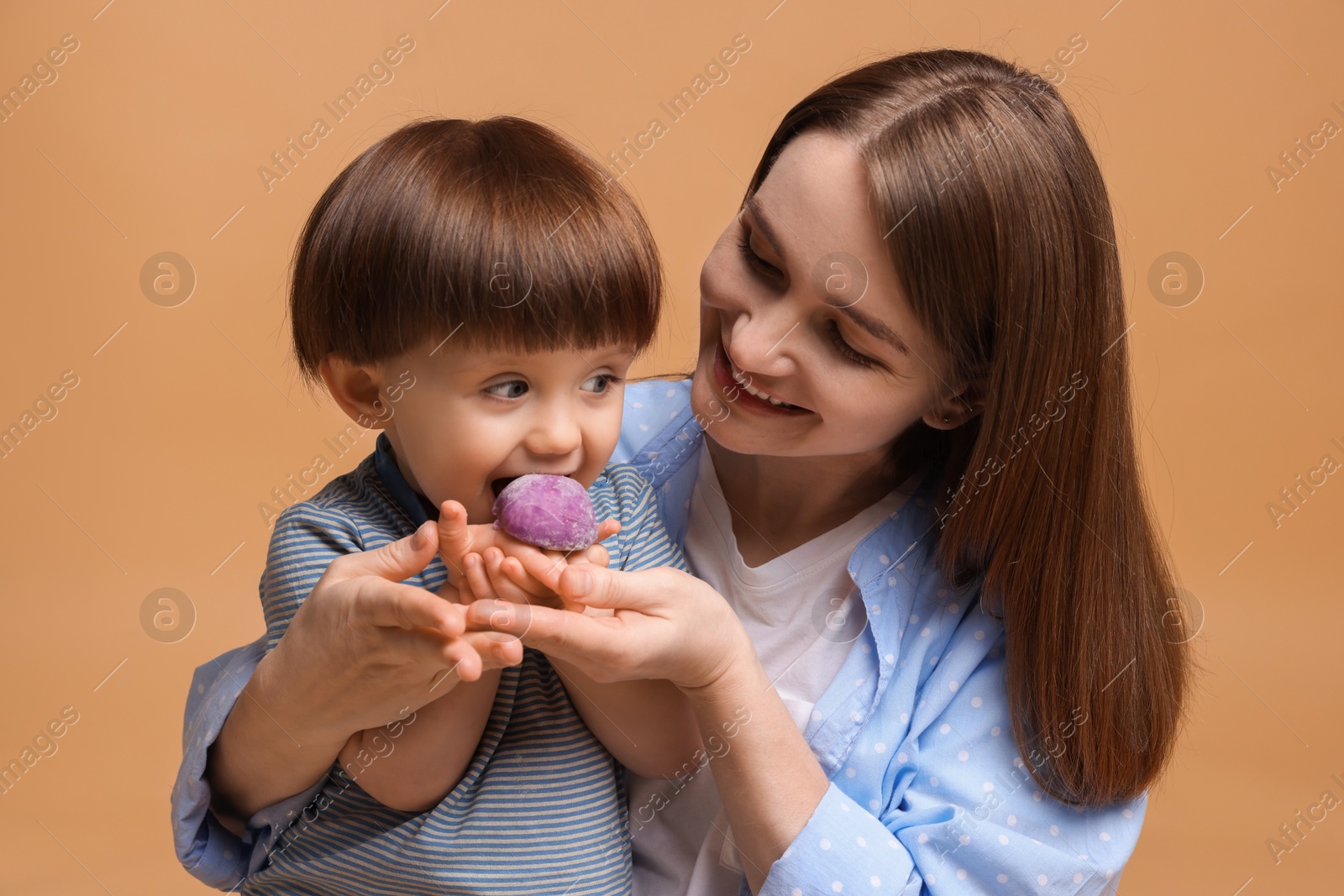 Photo of Mother and baby eating tasty mochi on brown background