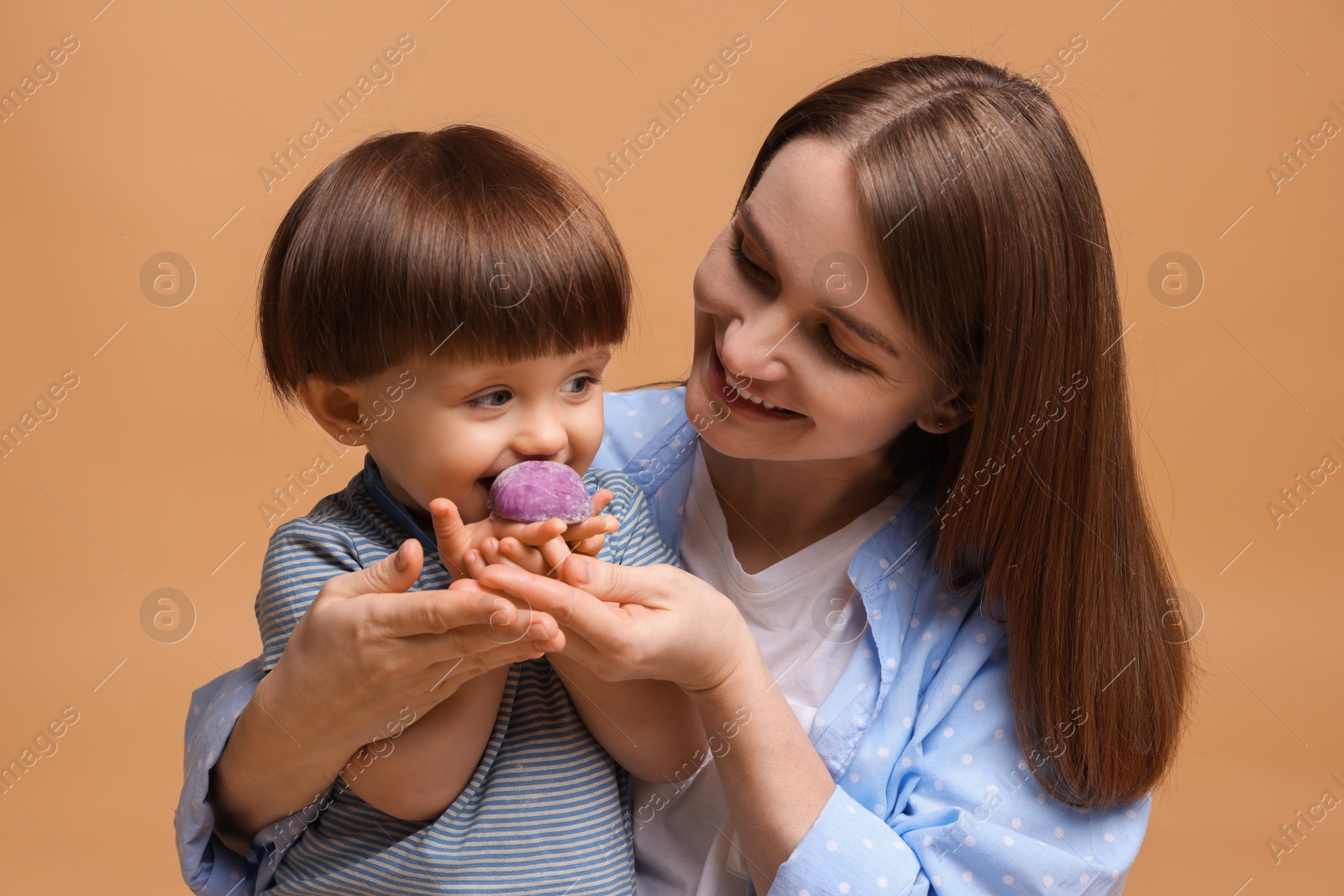 Photo of Mother and baby eating tasty mochi on brown background