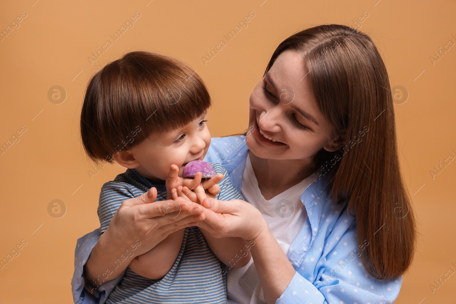 Photo of Mother and baby eating tasty mochi on brown background