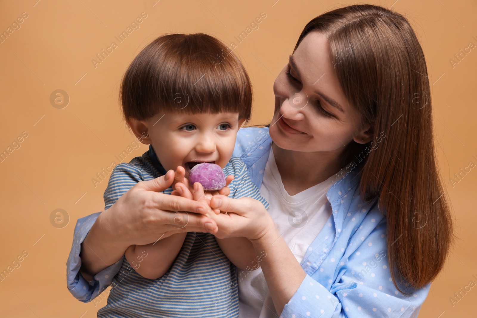 Photo of Mother and baby eating tasty mochi on brown background