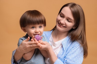 Photo of Mother and baby eating tasty mochi on brown background