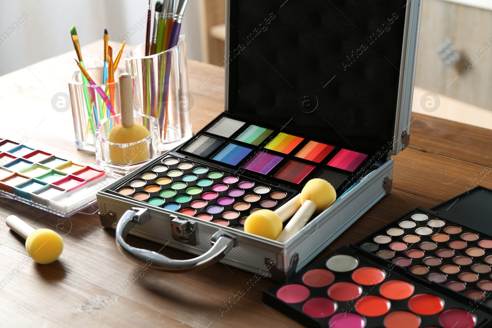 Photo of Face paints and tools on wooden table indoors, closeup