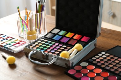 Photo of Face paints and tools on wooden table indoors, closeup