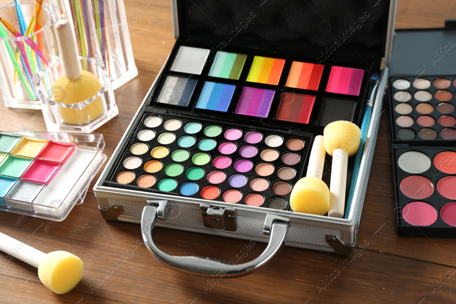 Photo of Face paints and tools on wooden table, closeup