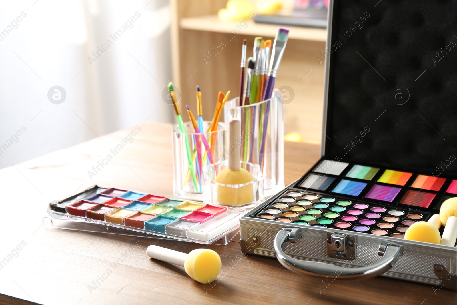 Photo of Face paints and tools on wooden table indoors, closeup. Space for text