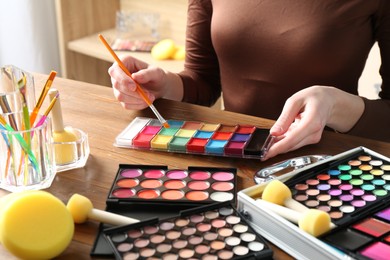 Photo of Professional artist with face painting products and tools at wooden table, closeup