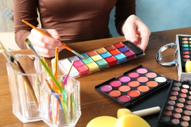 Photo of Professional artist with face painting products and tools at wooden table, closeup