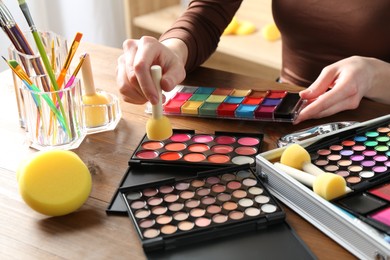 Photo of Professional artist with face painting products and tools at wooden table, closeup