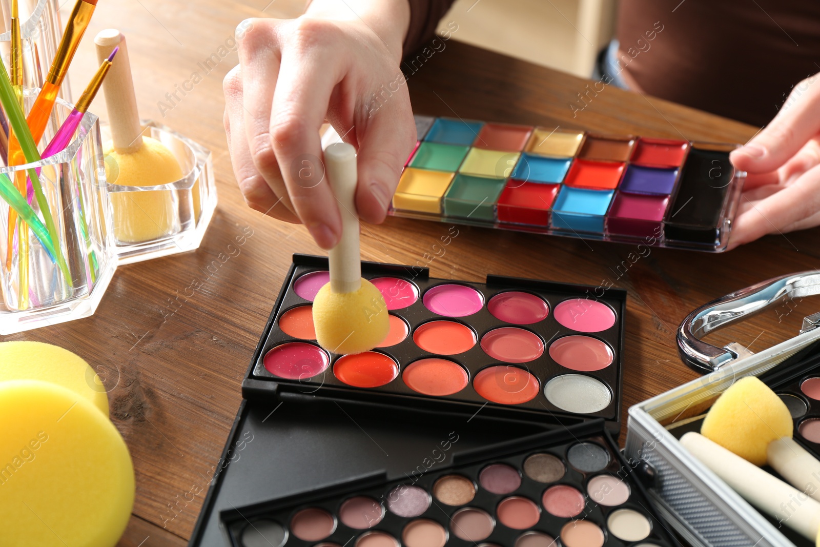 Photo of Professional artist with face painting products and tools at wooden table, closeup