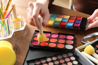 Photo of Professional artist with face painting products and tools at wooden table, closeup