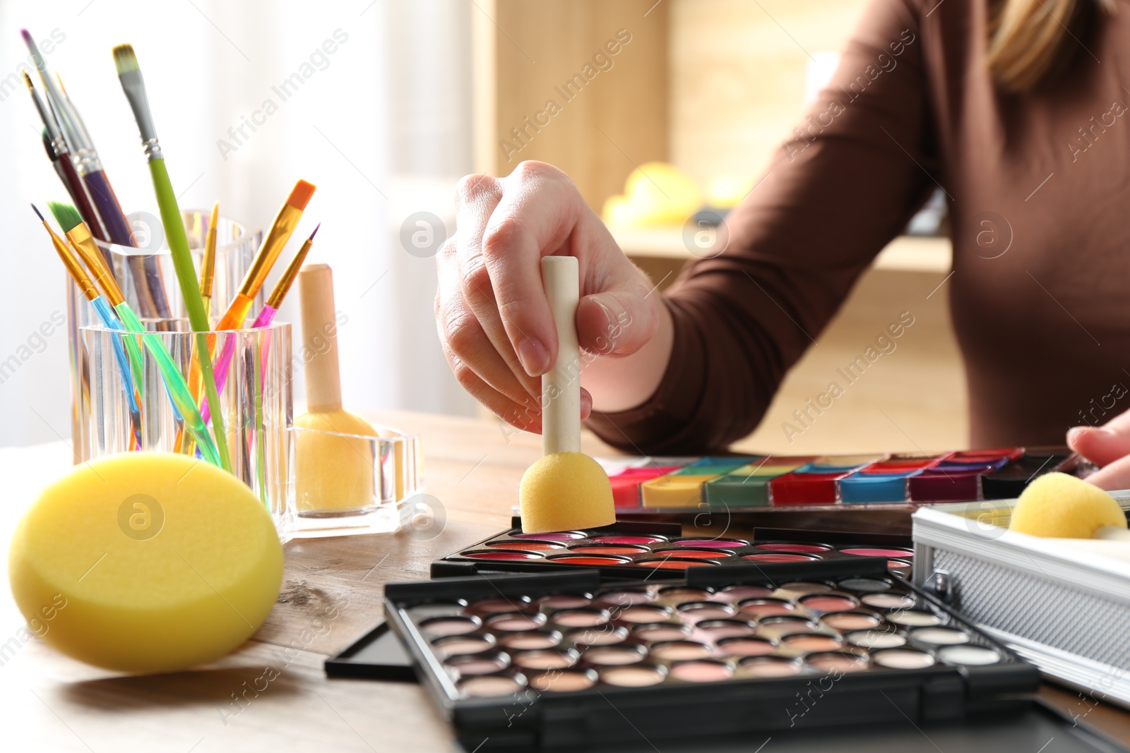 Photo of Professional artist with face painting products and tools at wooden table, closeup