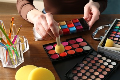 Photo of Professional artist with face painting products and tools at wooden table, closeup