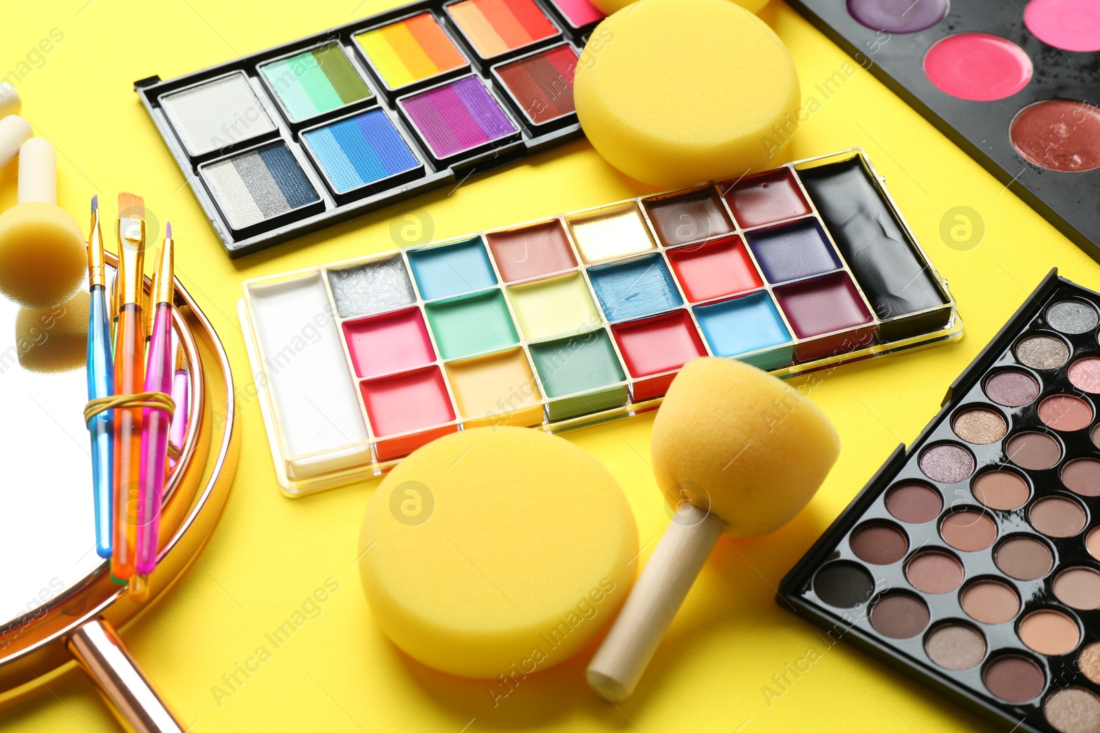 Photo of Face paints and tools on yellow background, closeup