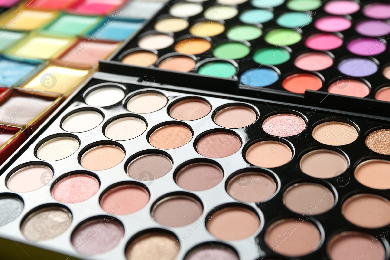 Photo of Palettes with beautiful eyeshadows as background, closeup