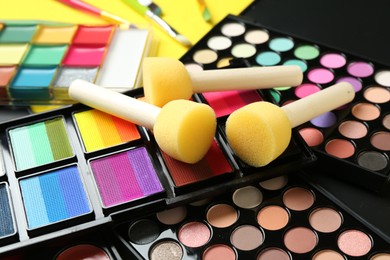 Photo of Face paints, tools and makeup products on yellow background, closeup