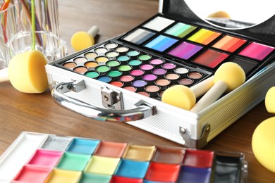 Photo of Face paints and tools on wooden background, closeup