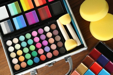 Photo of Face paints and tools on wooden background, closeup