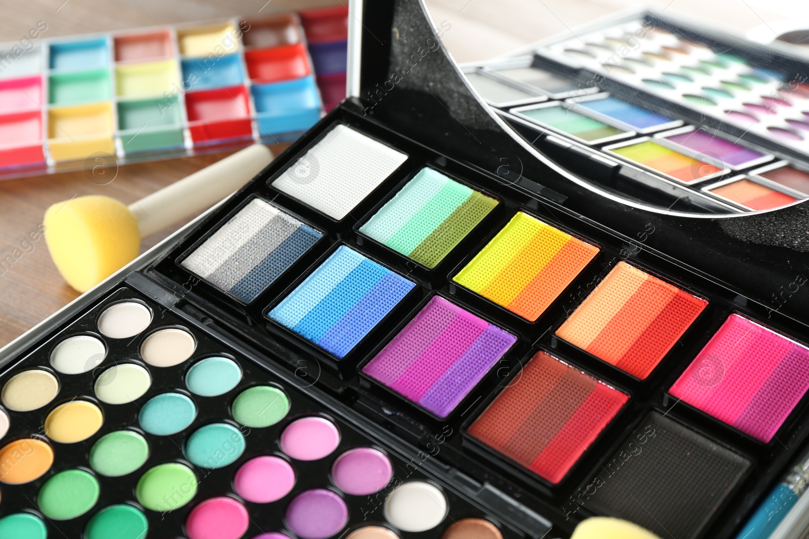 Photo of Face paints and tools on wooden background, closeup