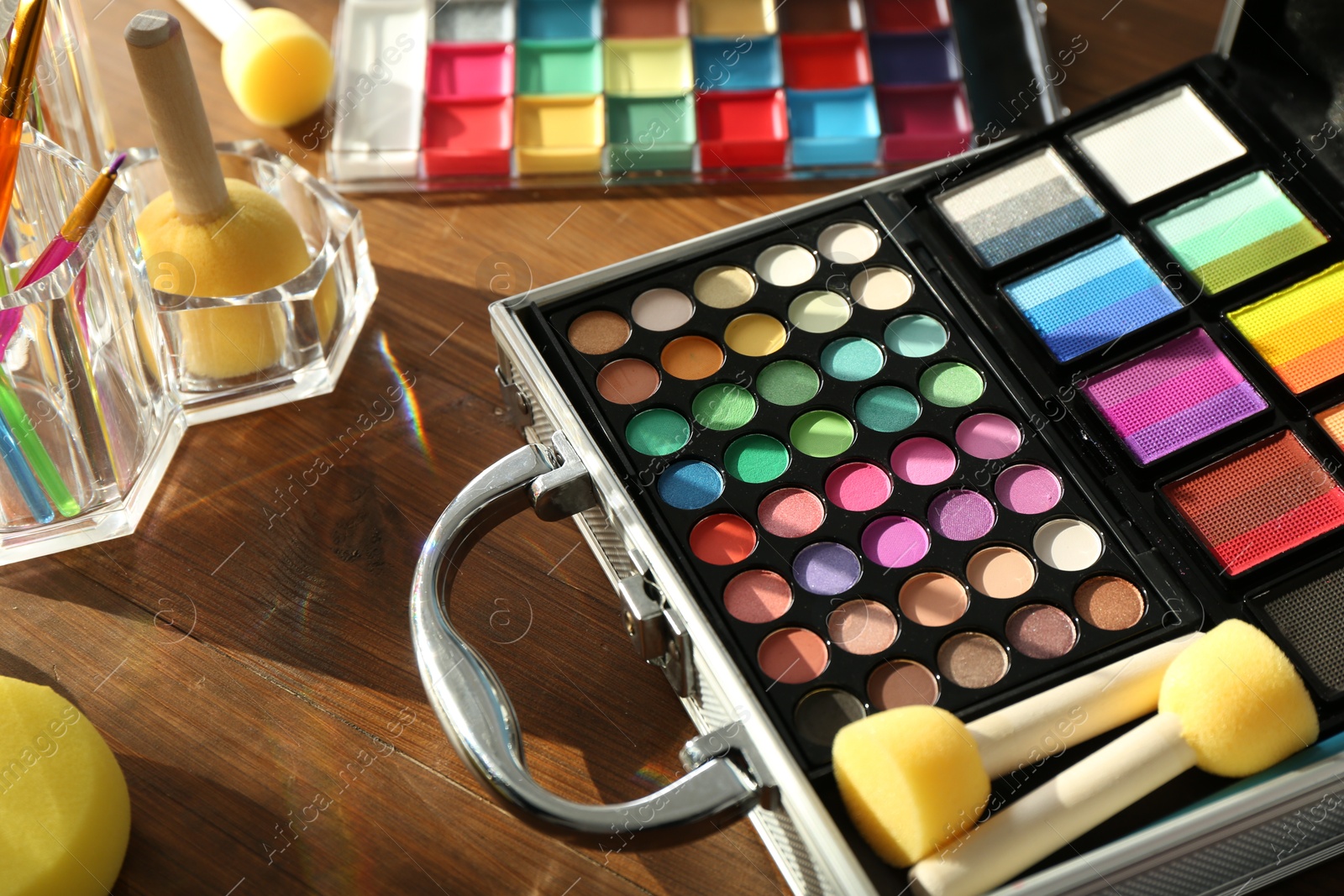 Photo of Face paints and tools on wooden background, closeup