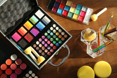 Photo of Face paints and tools on wooden background, flat lay