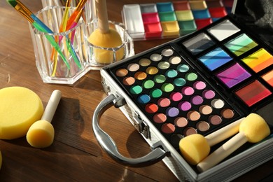 Photo of Face paints and tools on wooden background, closeup