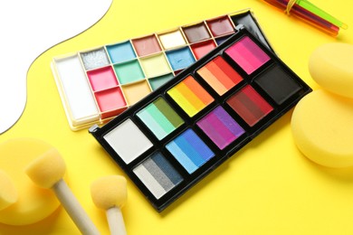 Photo of Face paints and tools on yellow background, closeup