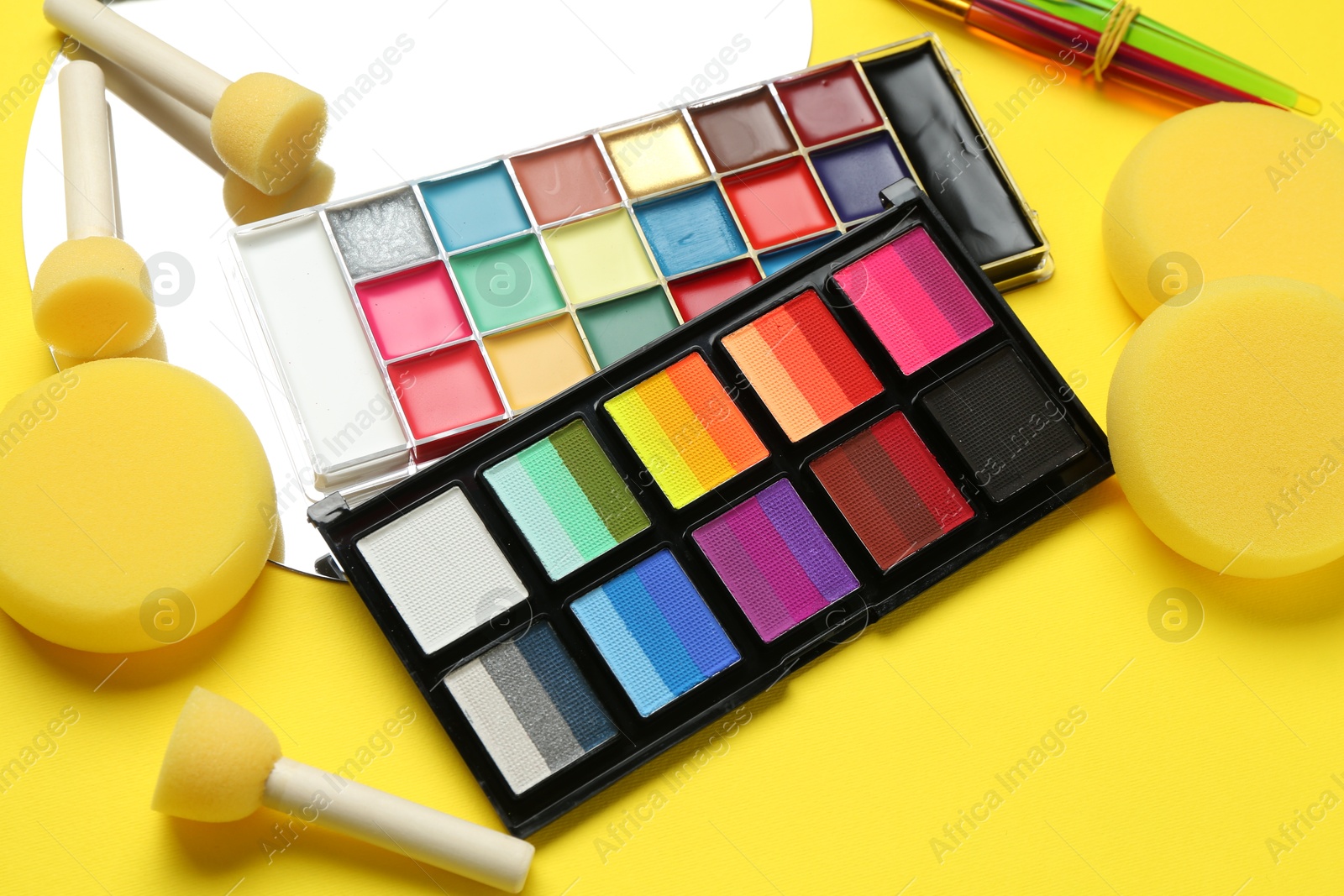 Photo of Face paints and tools on yellow background, closeup