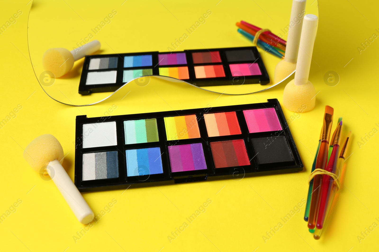 Photo of Face paints and tools on yellow background, closeup