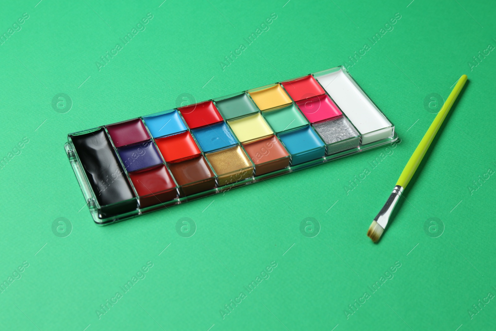 Photo of Face paints and brush on green background