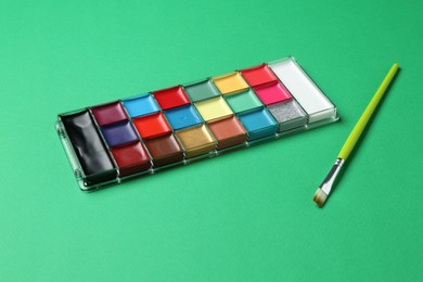 Photo of Face paints and brush on green background