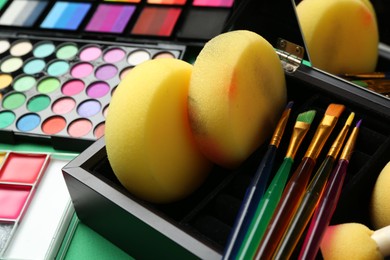 Photo of Face paints, tools and makeup products on green background, closeup