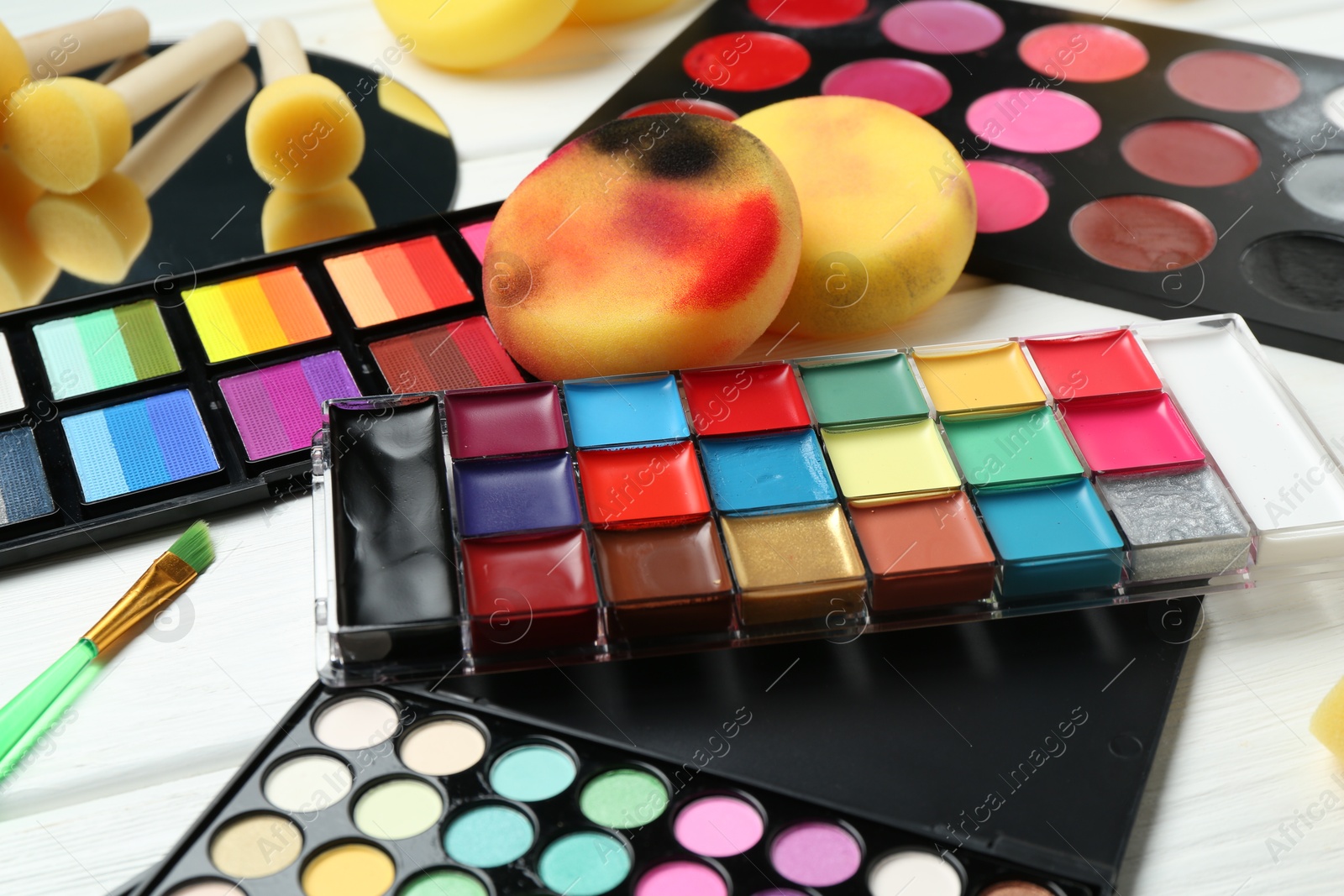 Photo of Face paints, tools and makeup products on white background, closeup