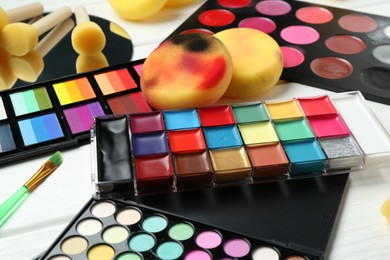 Photo of Face paints, tools and makeup products on white background, closeup