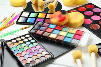 Photo of Face paints, tools and makeup products on white background, closeup