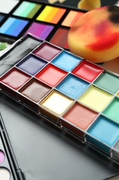 Photo of Colorful face paints and tools on table, closeup